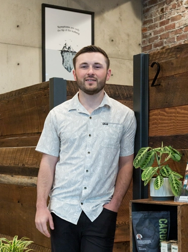 Chiropractor Dakota Turgeon leaning against a wood wall